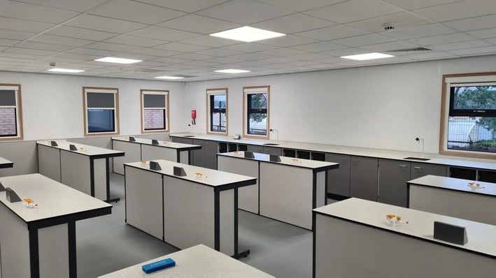 Modular science laboratory classroom with lab benches, and cabinets along the walls, and windows.