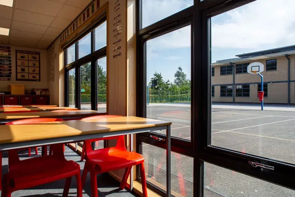Modern modular classroom interior with large windows, desks and chairs, bringing natural light into a school learning space