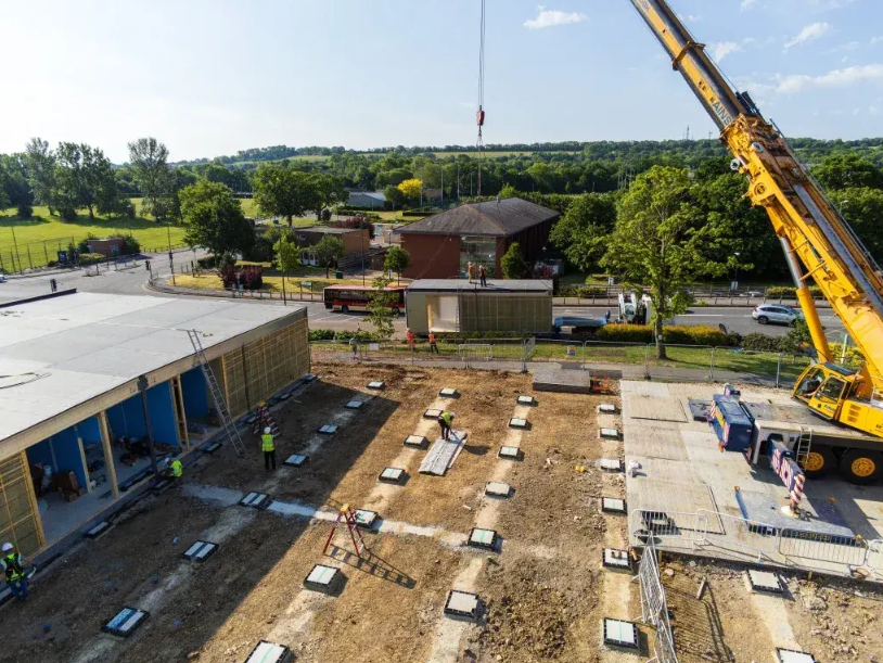 A crane on a site building a modular hospital building.