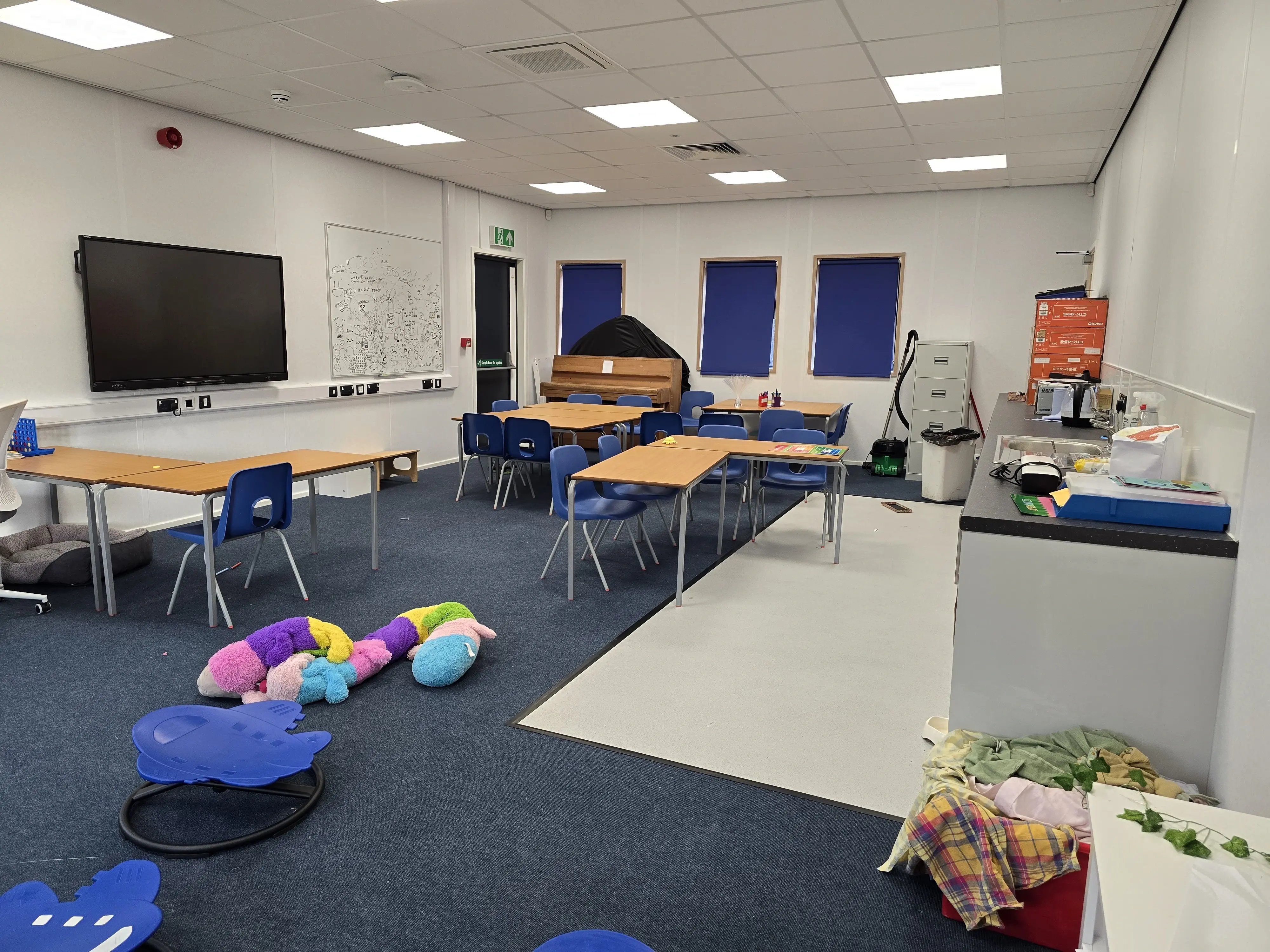 Interior of a permanent modular classroom with flexible teaching space, interactive display, group tables and integrated kitchenette.