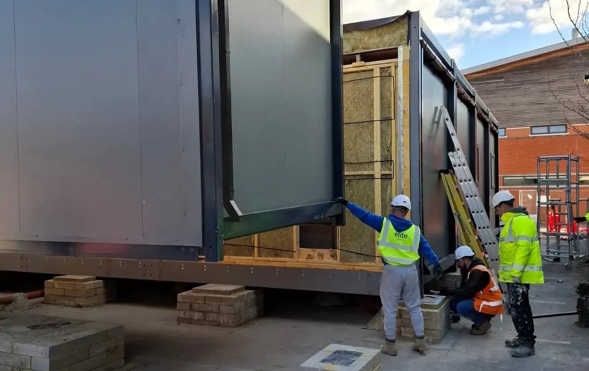 Installation of the temporary decant modular mortuary facility at St Richard's Hospital, showing Elite Systems GB engineers connecting modular building sections during onsite construction.
