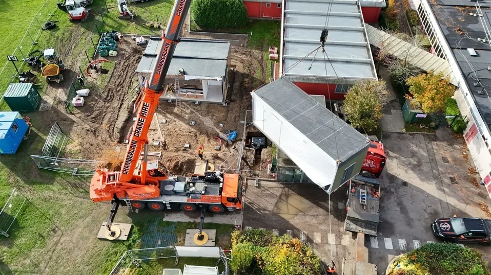 Mobile crane installing a permanent modular building on an existing operational site