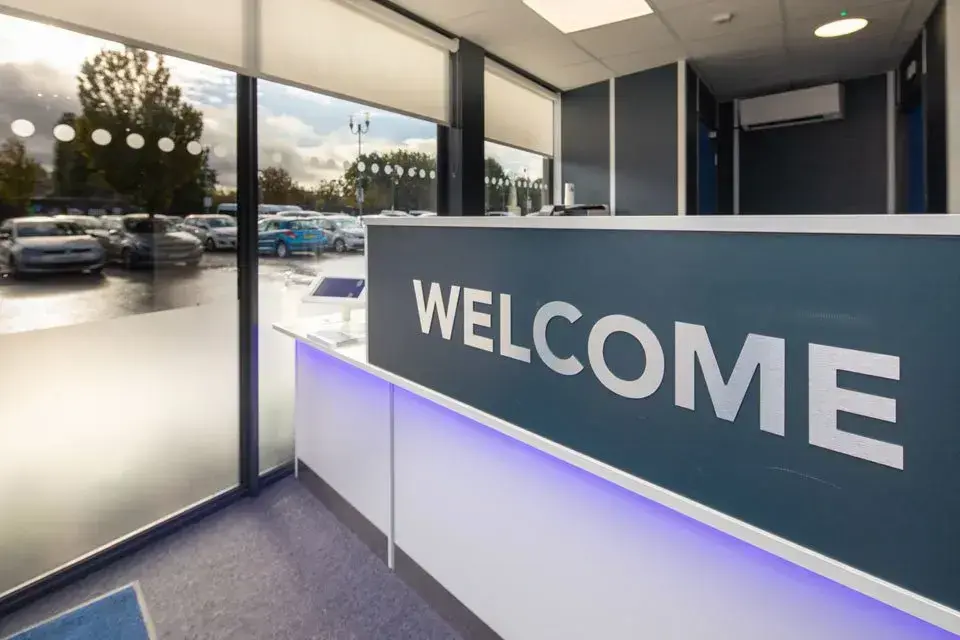 Modern commercial reception area with illuminated welcome desk and branded interior signage.