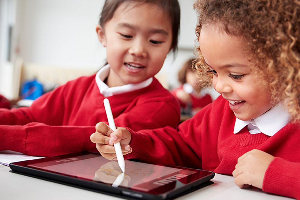 two primary school aged children using a tablet in the classroom